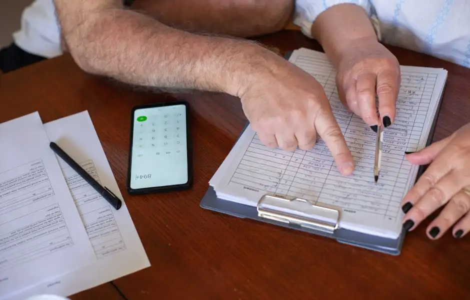 Couple relisant un contrat d'assurance emprunteur devant des documents bancaires et une calculatrice
